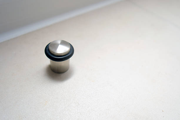 Metal door stop with black rubber ring on light floor. Modern home hardware protection. Interior floor accessory for domestic property.