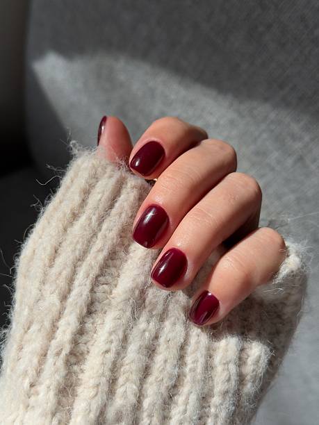 Woman showing her freshly done dark red manicured nails
