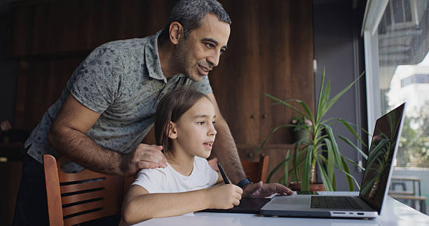 istock Father teaching his child daughter to draw digital pictures using graphics tablet, digitized pen and laptop computer 2239172894