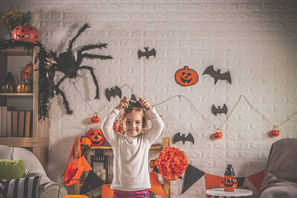 Young child with witch hat among Halloween decorations in a cozy festive home setting