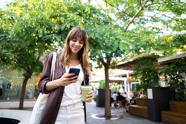 istock Woman enjoying a matcha latte and communicating with a smartphone while strolling in an outdoor plaza with green trees 2239183279