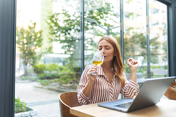 istock Beautiful Woman Using Computer and Enjoying Wine 2239184882