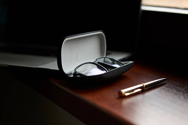 istock Glasses in open case on wooden desk with pen 2239195691