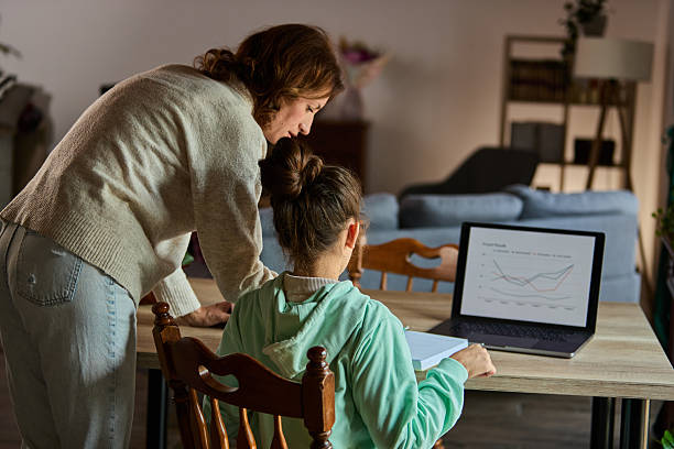 istock Mother Helps Daughter with Laptop Graphs during a Home Study Session 2239199106