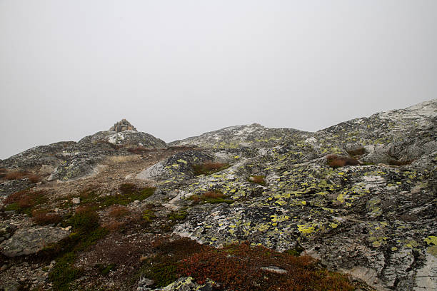 Man made cairn marker on a misty morning in Norway. Beautiful stone in the lower part of the image. Background completely covered in fog.