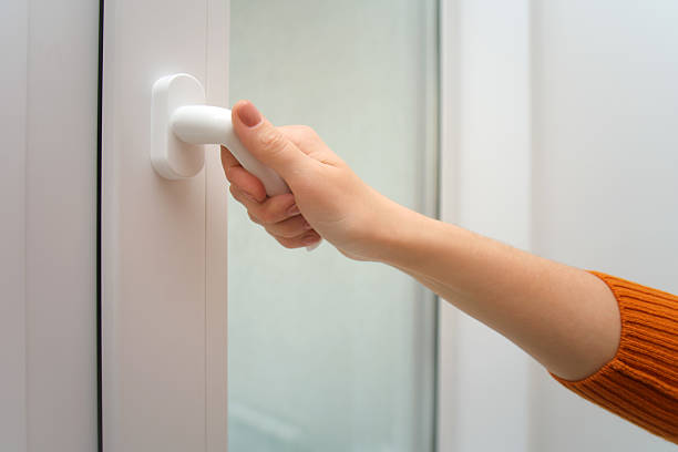 istock Woman closing or opening a white plastic window handle. Home interior clean close up shot with modern furnishing and daylight. 2239200757