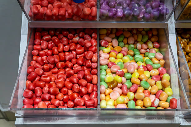 Colorful candies in transparent store containers, assorted sweets displayed in confectionery shop shelves with vibrant colors and glossy coating