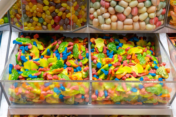 Colorful crocodile-shaped gummy candies in transparent store containers, assorted sweets displayed in confectionery candy shop with vibrant multicolored treats