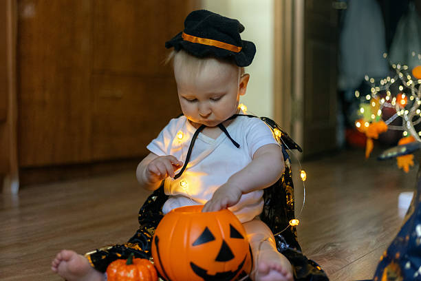 istock Adorable Baby in Witch Costume Playing with Pumpkin 2239220746