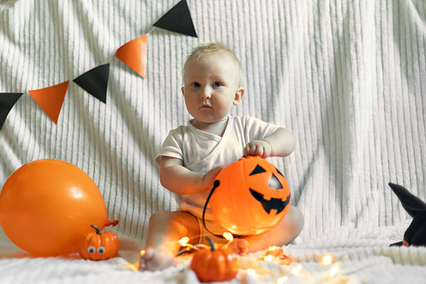 istock Baby in Halloween Hat Playing with Pumpkin Balloon 2239220920