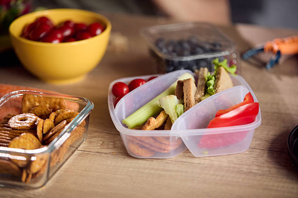 istock Healthy snack prep: fresh veggies, crackers, and fruit in lunch containers on a wooden table 2239222420