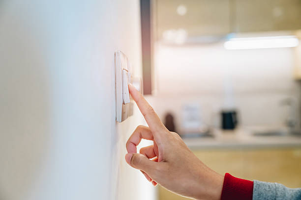 istock Save energy concept. Hand Reaching to Turn Off Light Switch in Modern Kitchen with Soft Natural Lighting 2239223980