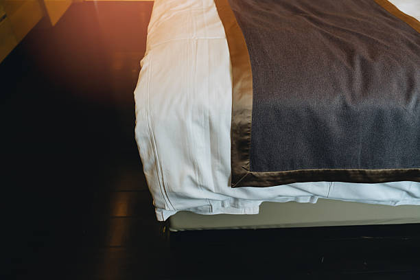 istock Cozy Bedroom Setting with Elegant Brown Throw Blanket Draped Over a Plush White Bedspread in Warm Lighting 2239224010