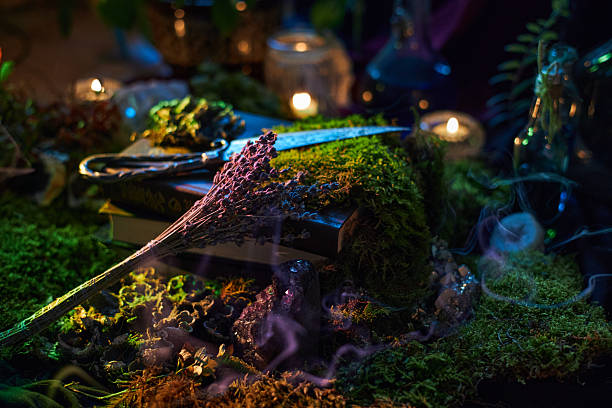 istock mystical tabletop scene features open books, dried herbs, and glowing candles. Soft smoke lingers as natural elements create a tranquil, magical environment 2239225456