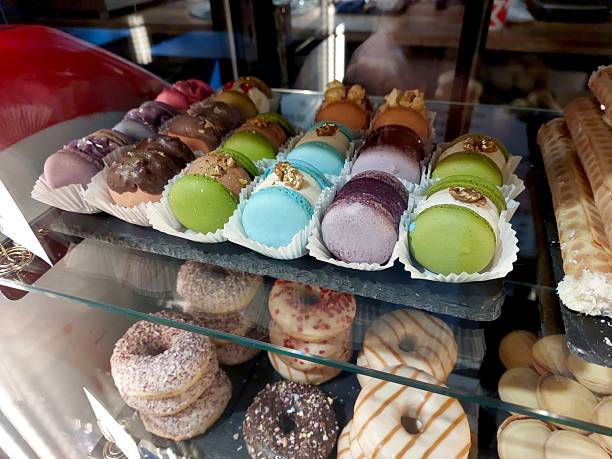 istock Colorful Macaroons Displayed in a Bakery Case on a Sunny Day in a Bustling Market 2239227566
