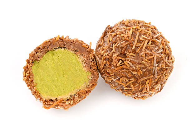 A Dubai chocolate covered cookie with green filling is shown with a bite taken out of it. The cookie is covered in brown sprinkles