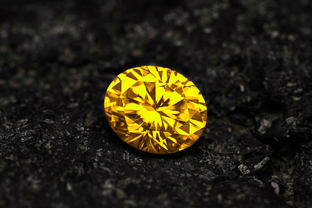 istock A yellow diamond is sitting on a black rock 2239229168