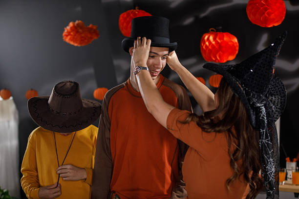 Candid shot of teenage boys and their mother having bonding moments when trying out hats for Halloween costumes.