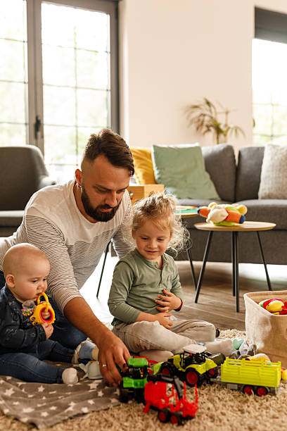 istock Man sitting on the floor, playing with his two little sons 2239240851