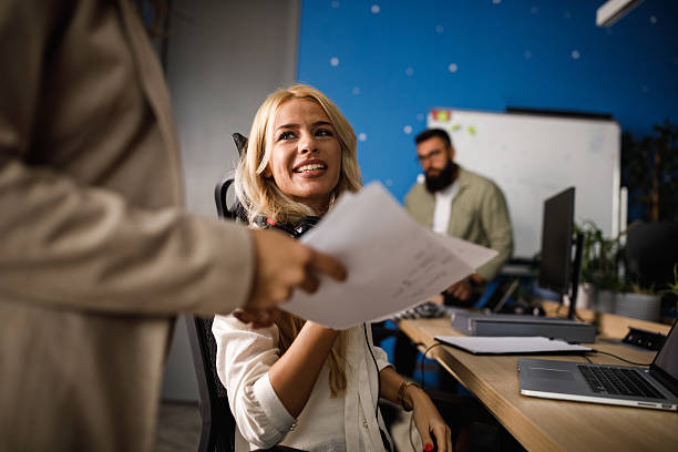 istock Friendly office moment: smiling woman in headset receives documents during a collaborative meeting 2239248368