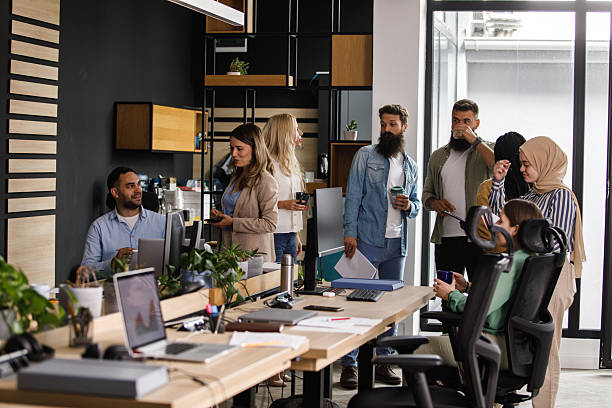 istock Diverse team of coworkers sharing a casual office conversation in a modern open-plan workspace 2239248397