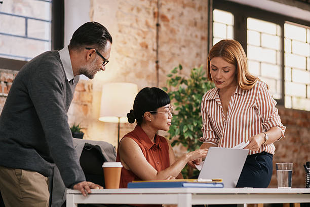 istock Adult Professionals Collaborating In Modern Office With Laptop, Coffee, And Documents, Focused, Supportive Mood, Together 2239252793