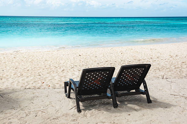 Beautiful Caribbean beach on Saona island, Dominican Republic. View of tropical idyllic summer landscape with two beach chaise lounges, sea coast and white sand