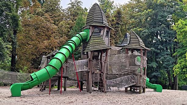 A vibrant and colorful playground featuring a large green slide along with beautiful wooden castlelike structures