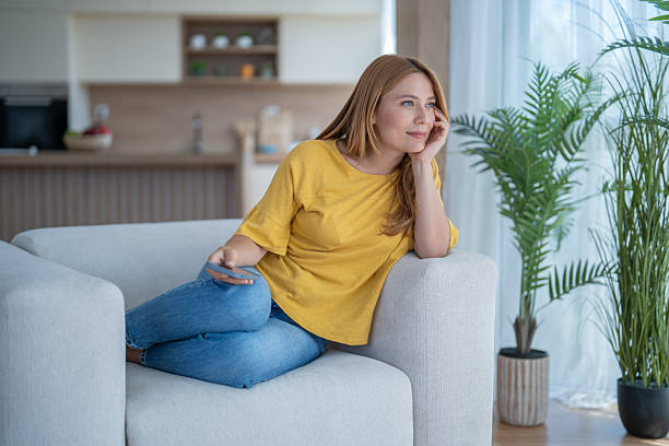 istock Woman relaxing on sofa and holding remote control, daydreaming 2239265714
