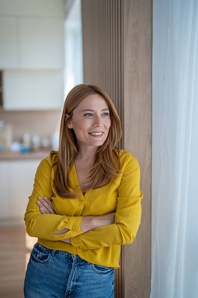 istock Smiling woman looking away while leaning against wall at home 2239265721