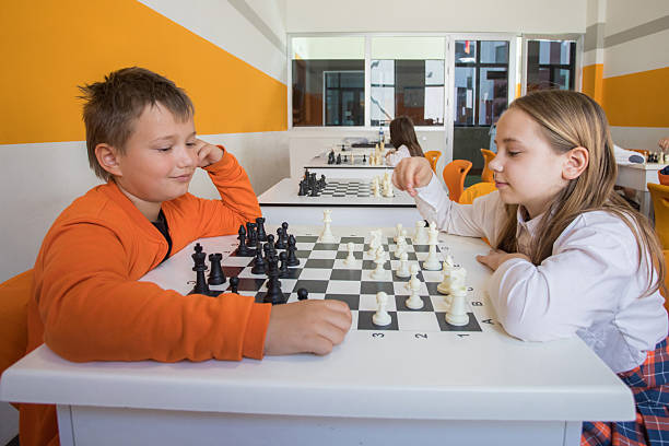 Happy children school student playing chess in classroom at school