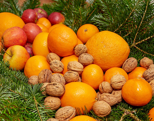 istock Fresh oranges, ripe apples, and walnuts with festive spruce branches 2239266077