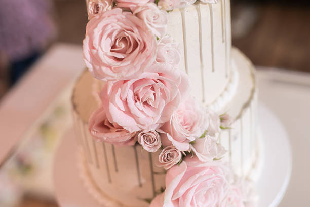 Photos of a beautiful wedding cake with white roses on the table on a luxurious wedding day.