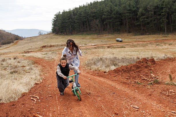 istock Devoted mother learning her son to ride a bicycle in nature 2239279902