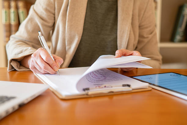 istock Woman's hands signing a contract on a clipboard while reviewing additional financial documents, indicating a successful business deal, loan approval, or real estate transaction 2239288864