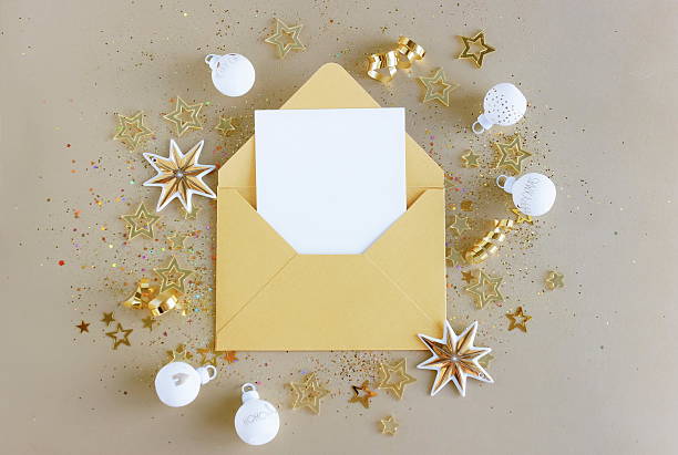 istock Envelope with blank paper card mockup inside top view and gold Christmas decor on beige background . Copy space 2239290991