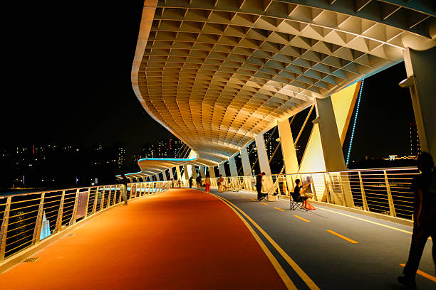 There are many people moving around on the pedestrian overpass at night