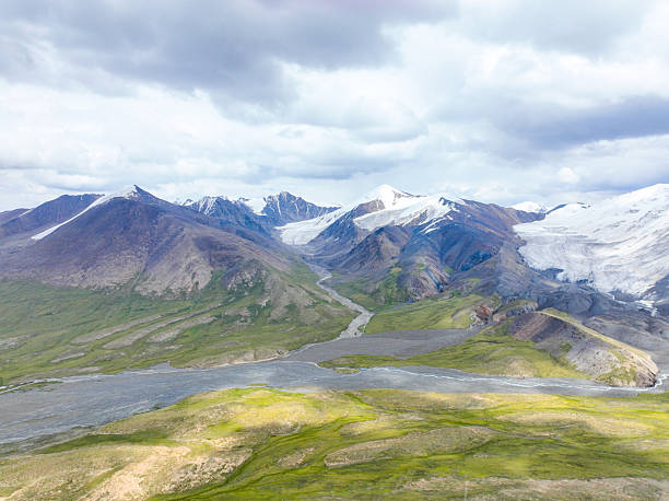 istock Glacier-capped mountains above a wide green river valley 2239298610