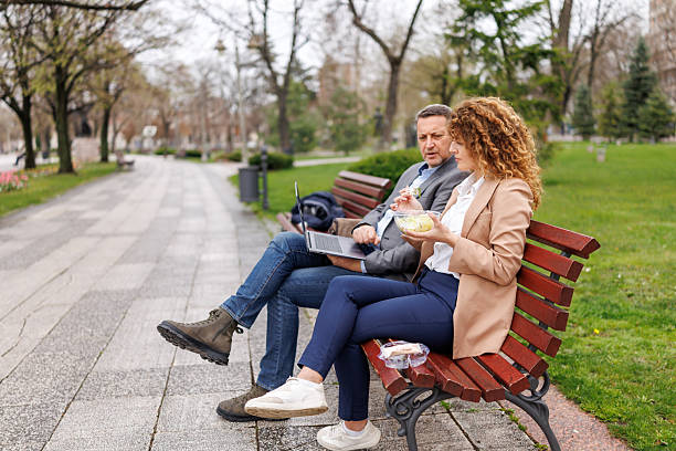 istock Business people using laptop while sitting on bench in the city 2239299133
