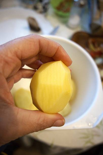 istock Peeled whole potato held in hand in kitchen 2239299734