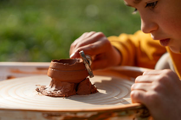 istock Child working clay on pottery wheel outdoors 2239303860