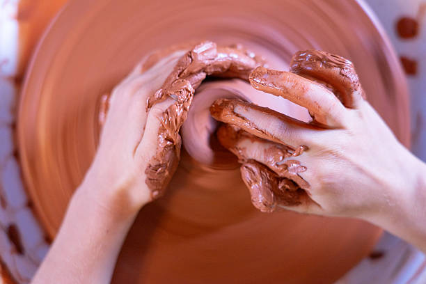 Potter is working on pottery wheel and making a clay pot