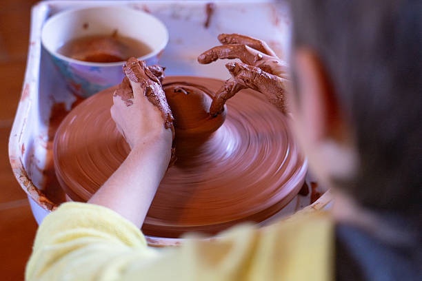 istock Child working on pottery wheel creating a clay pot 2239303906