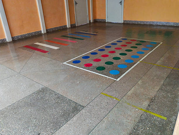 ​A spacious room with light orange walls and a tiled floor, where bright markings have been applied for children's games.