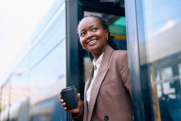 istock Smiling woman holding coffee cup exiting public bus 2239307647