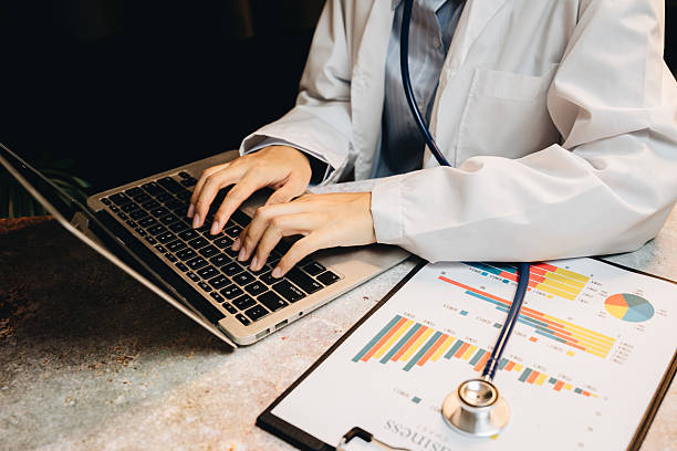 istock Doctor in White Coat Working on Laptop with Stethoscope and Medical Reports on Table for Health Care and Research Concepts 2239308222
