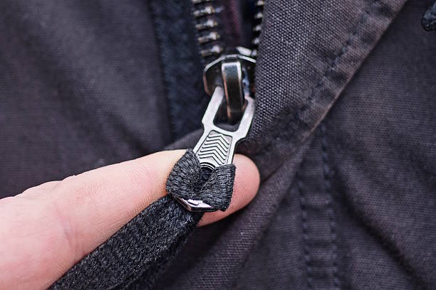 istock A finger holds one gray metal zip on black fabric 2239319555