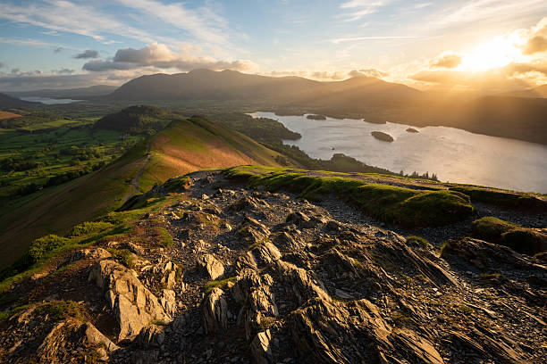 Amazing golden light breaking through dramatic clouds over Derwentwater, seen from popular viewpoint known as Catbells in the Lake District, UK.
