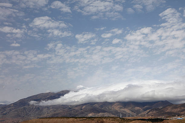 Mountain landscape with cloudy sky and dark clouds over the mountains in a dry plain. Village on the mountainside