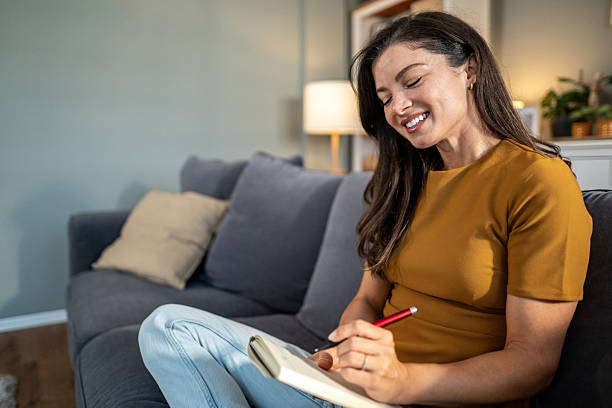 istock Woman smiling writing in daily journal notebook at home 2239326672